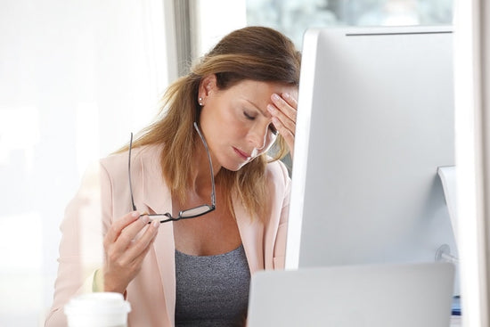A woman stressed at a computer because of adrenal fatigue