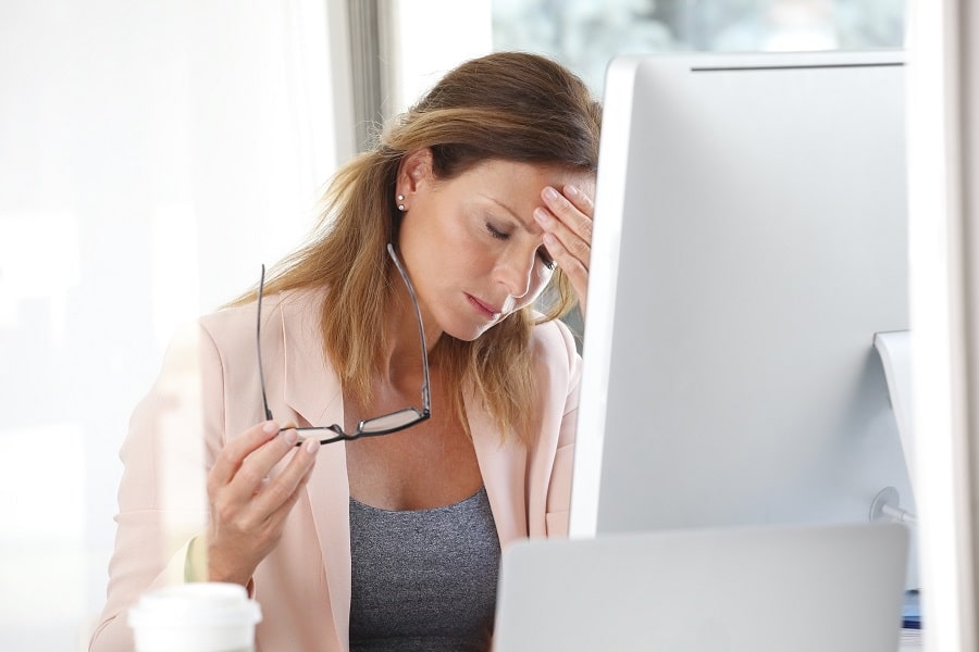 A woman stressed at a computer because of adrenal fatigue