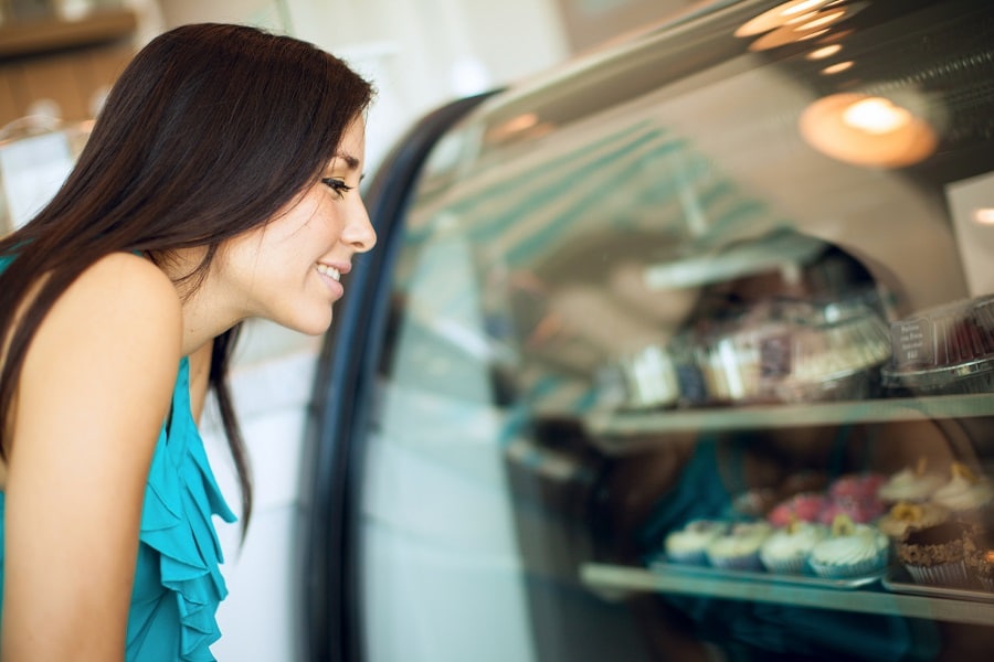 A woman looking at a case of cupcakes