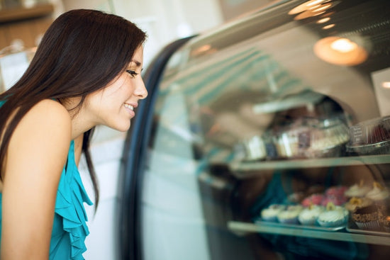 A woman looking at a case of cupcakes