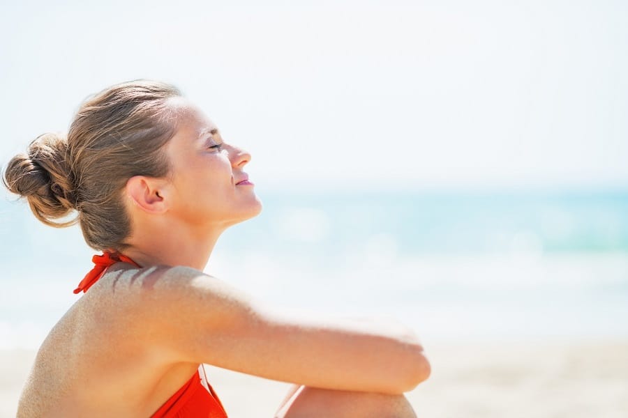 Woman sitting on the beach in the sun