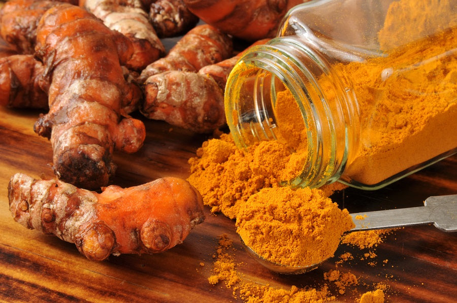 A jar of ground turmeric next to turmeric roots to add turmeric in your diet