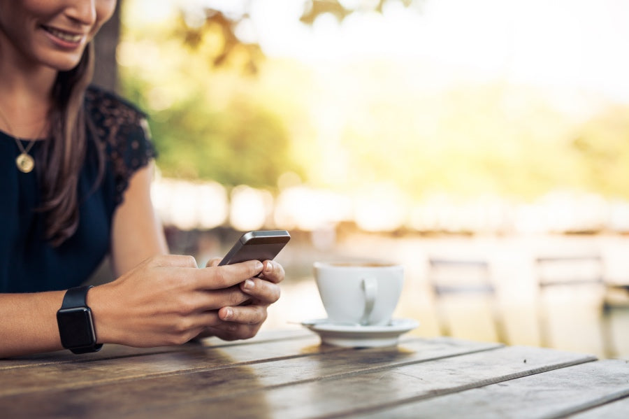 A woman texting and drinking tea