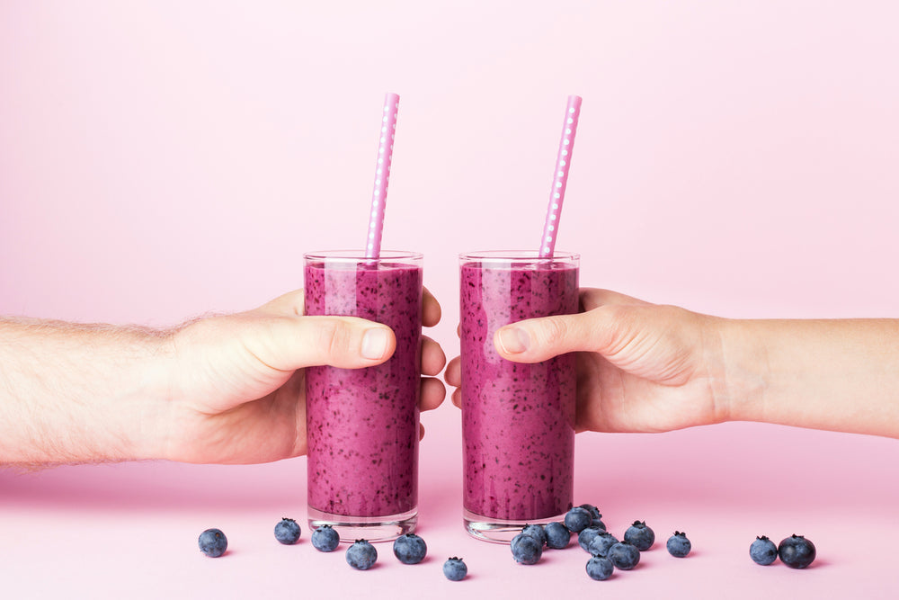 Two people holding blueberry smoothies