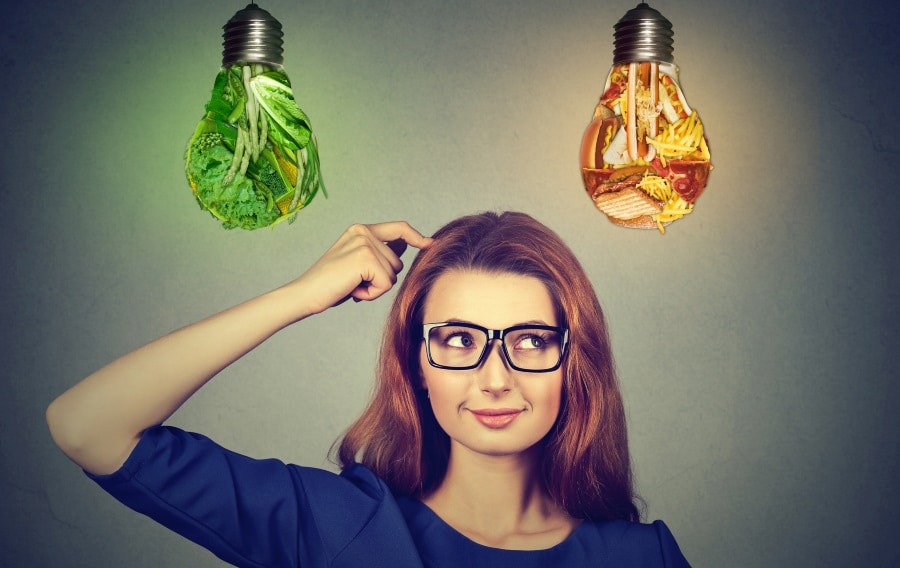 A woman standing under two lightbulbs made of vegetables