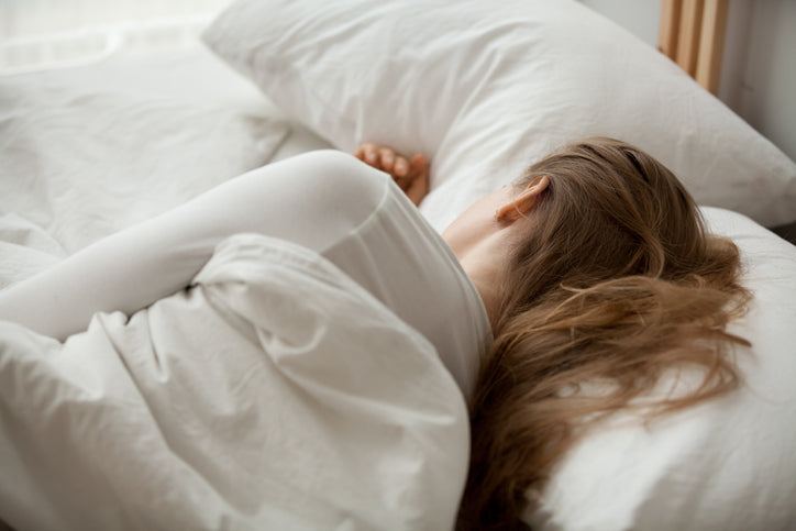 a woman lying in bed after eating foods good for sleep
