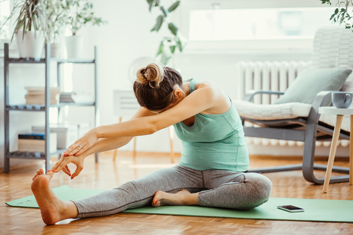 woman sitting on a yoga mat learning the best tips for exercising at home