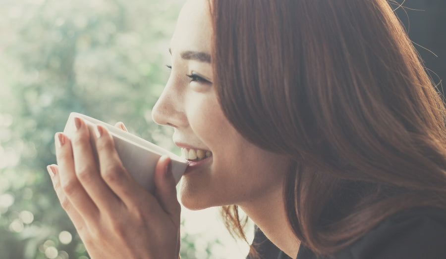 A woman smiling drinking tea