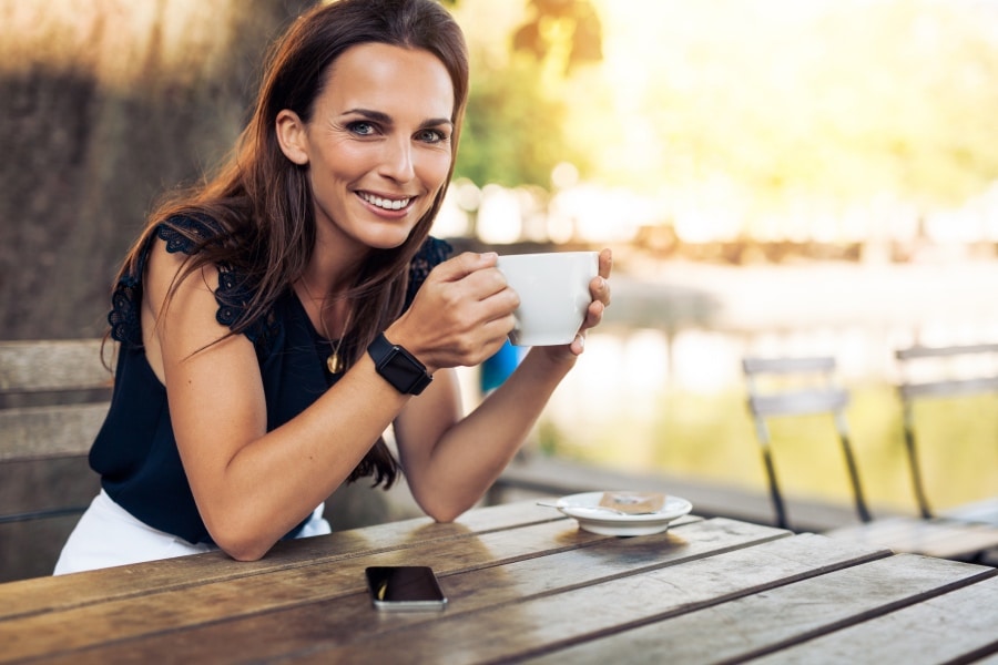 Woman sitting at a picnic table drinking coffee