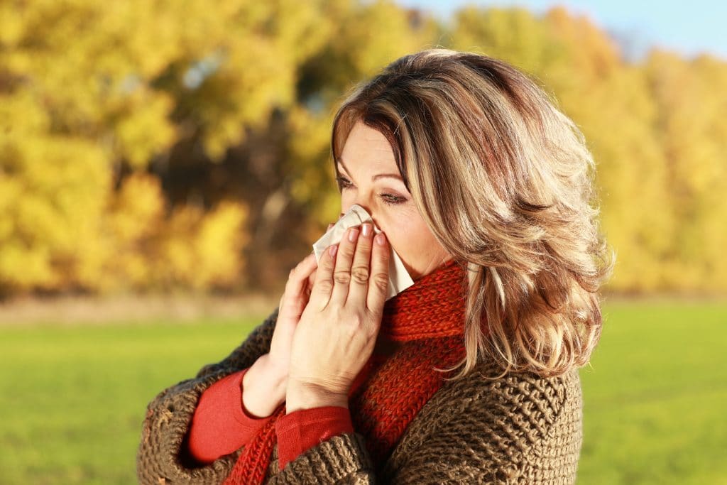 Woman blowing her nose outdoors