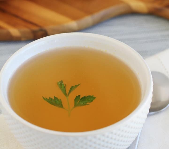 Broth in a white bowl with a single garnish