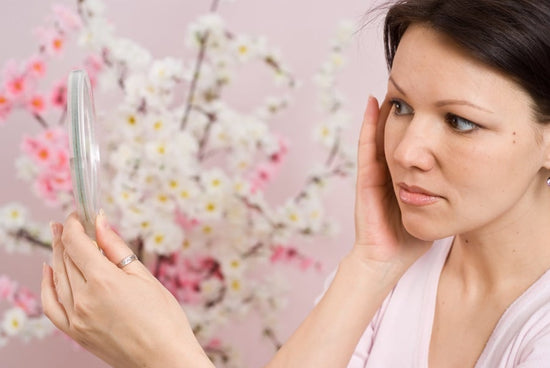 A woman looking at her face in a mirror