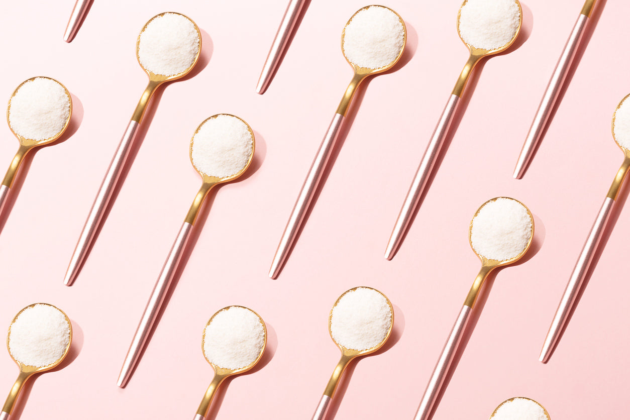 Found measuring spoons full of granules of gelatin on a pink background