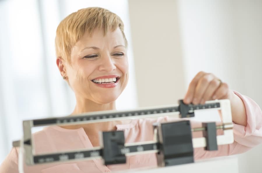 A woman smiling weighing herself