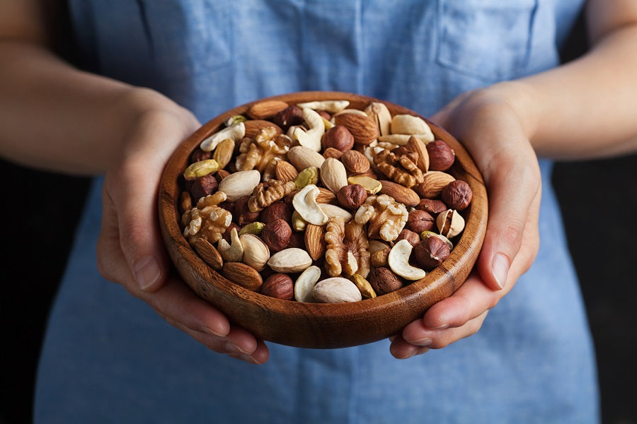 A woman in a blue dress with holding a bowl of nuts