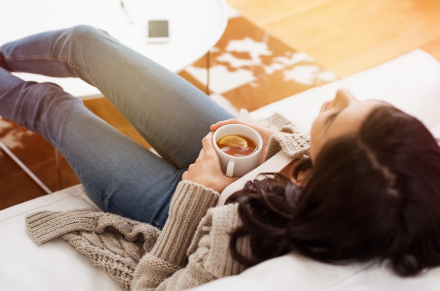 A woman laying on the couch with tea