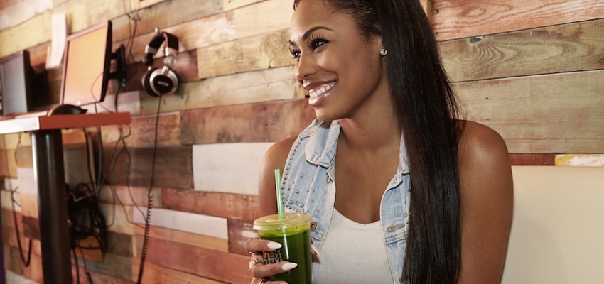 A woman smiling drinking a smoothie