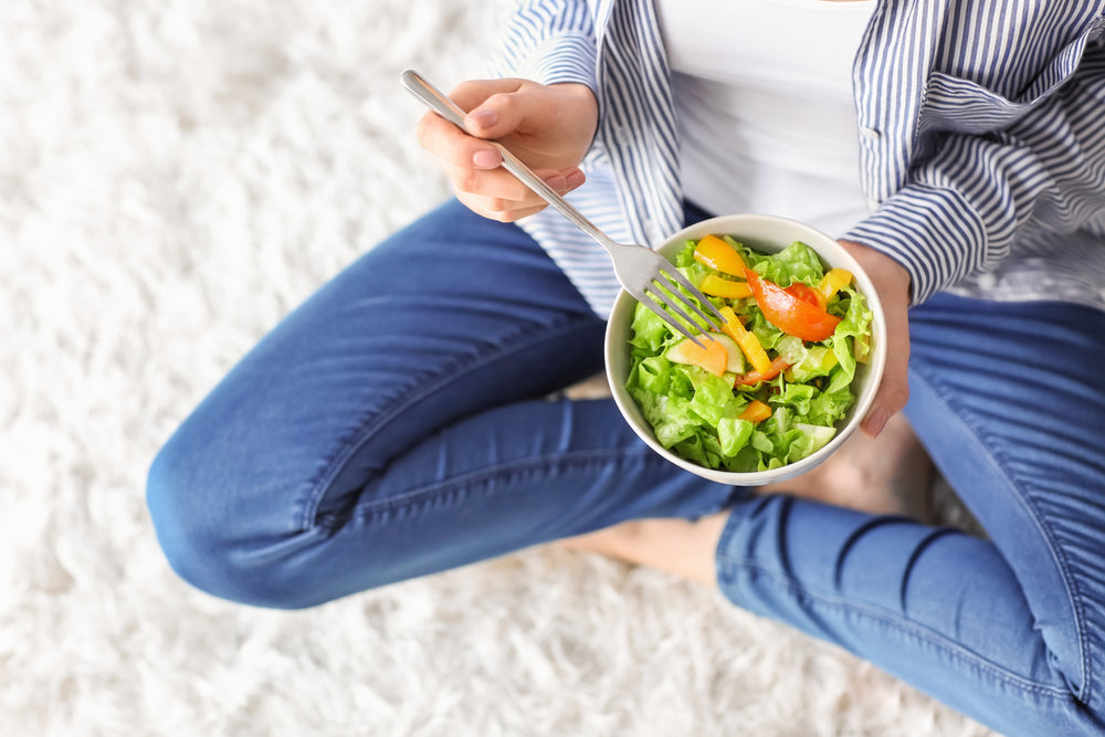 woman sitting down and eating salad
