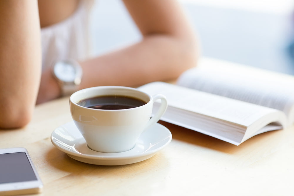 woman drinking coffee in morning while reading cleanse and reset