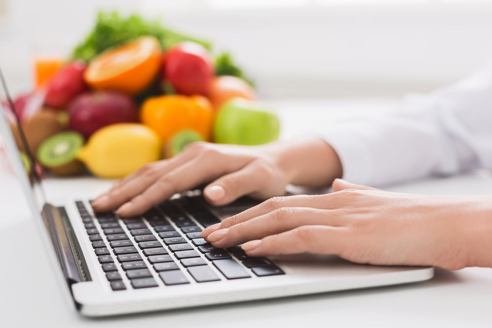 woman searching online with fruits and vegetables