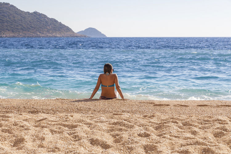 Women sitting on the beach at the edge of the ocean
