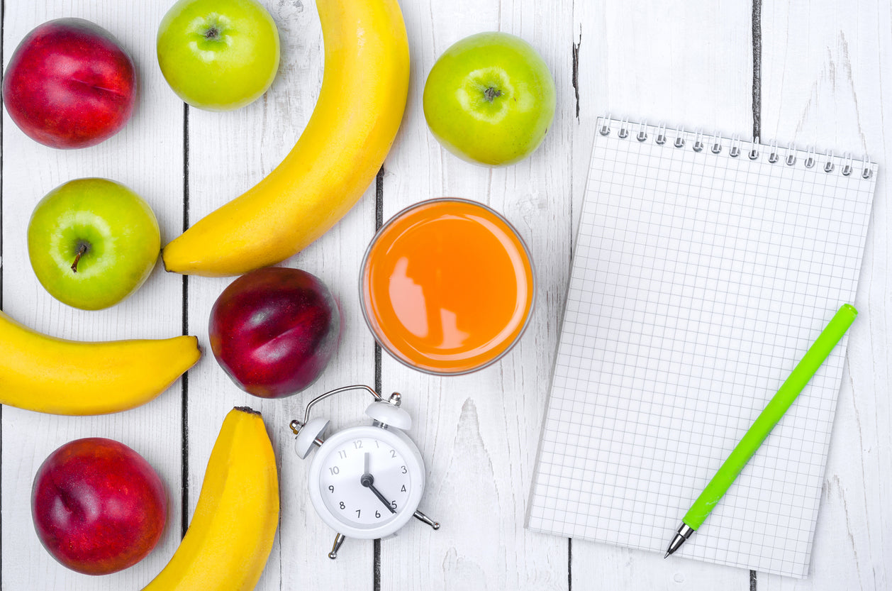 fruits and vegetables laid out next to notepad