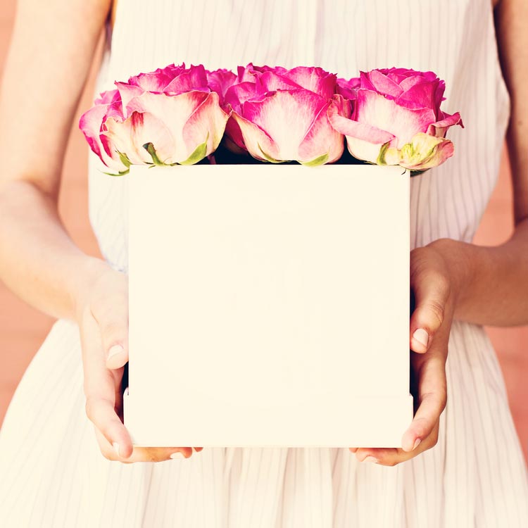 A woman in a dress holding a square vase of roses