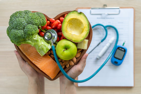 A heart shaped bowl with fruits and vegetables next to diabetes testing to show how obesity and immunity are connected.