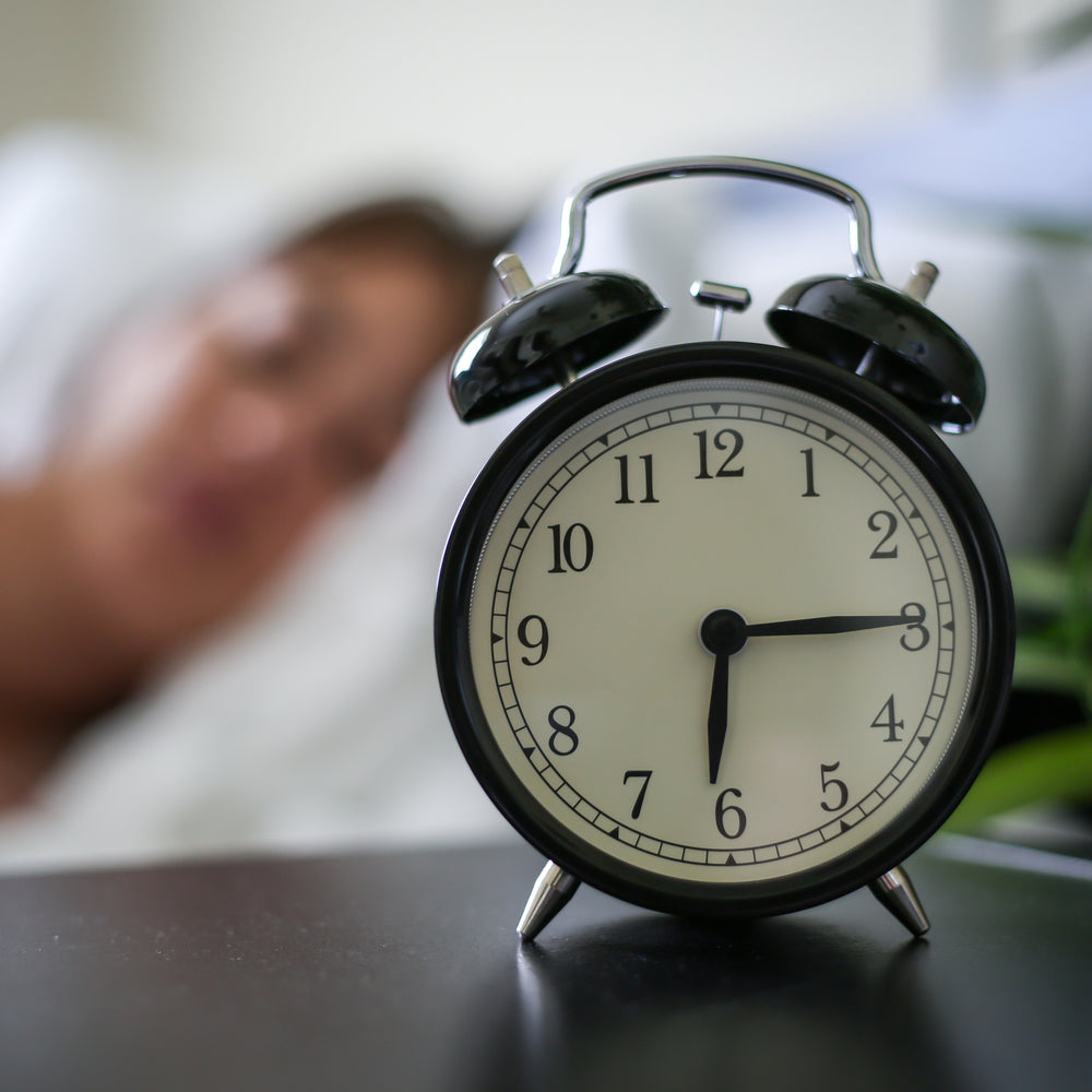 Alarm clock next to sleeping woman