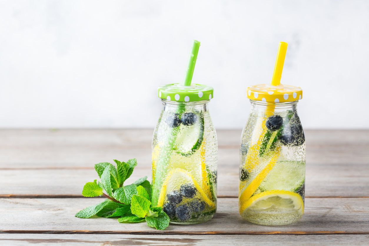 water with cucumbers, lemons, and blueberries in small bottles for Dr. Kellyann's Cleanse and Reset