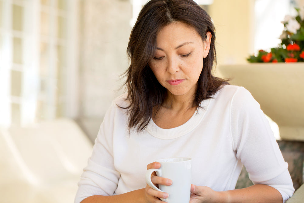 A woman drinking coffee thinking of ways to manage depression and anxiety naturally