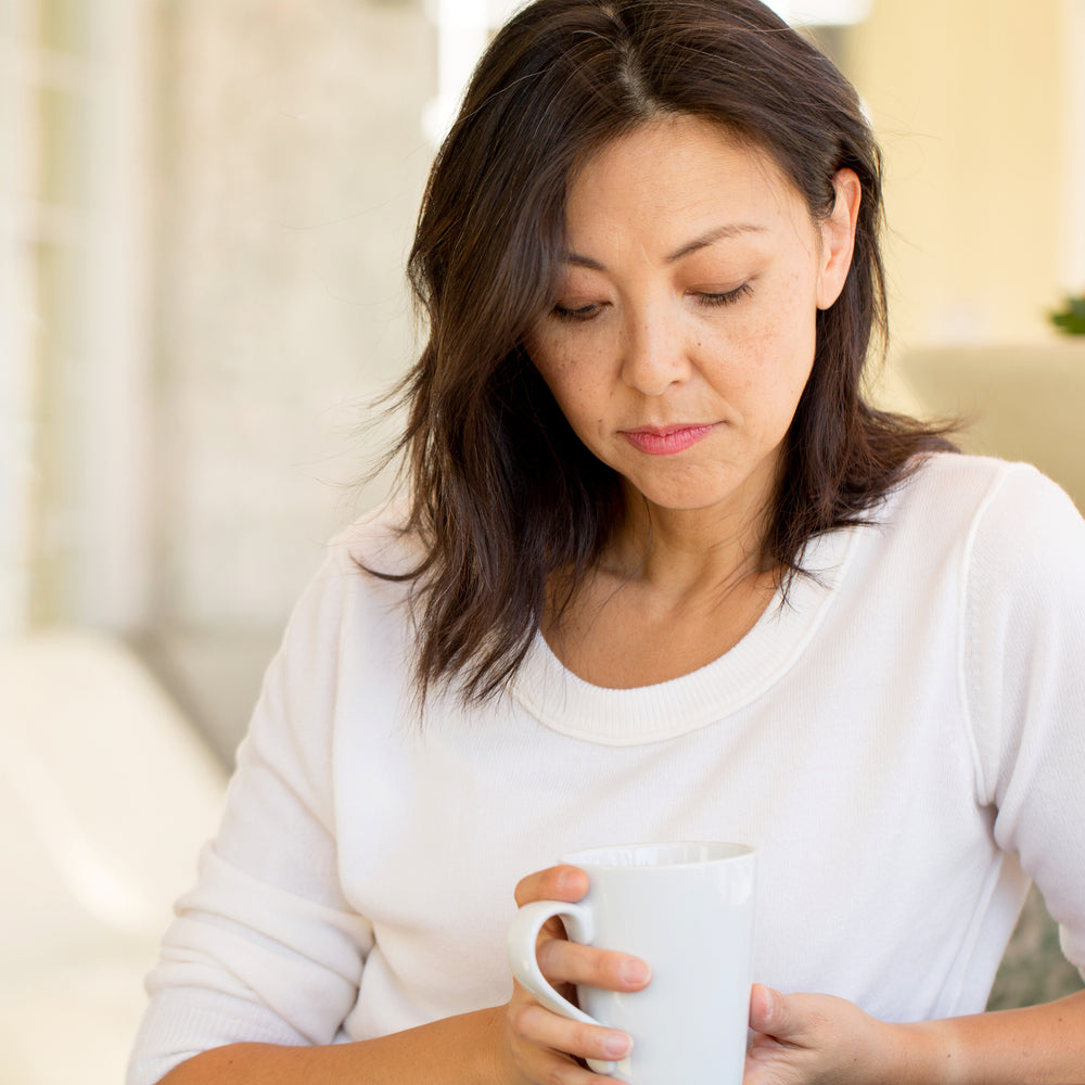 A woman drinking coffee thinking of ways to manage depression and anxiety naturally