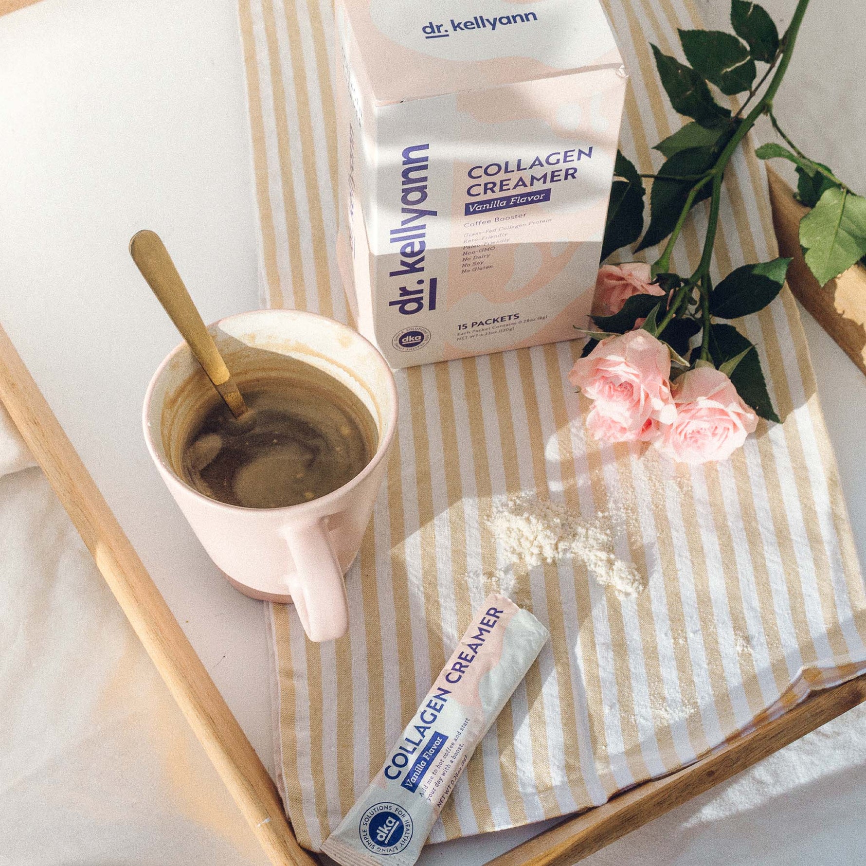 Collagen Creamer - Vanilla Package next to a coffee cup on a table with pink flowers